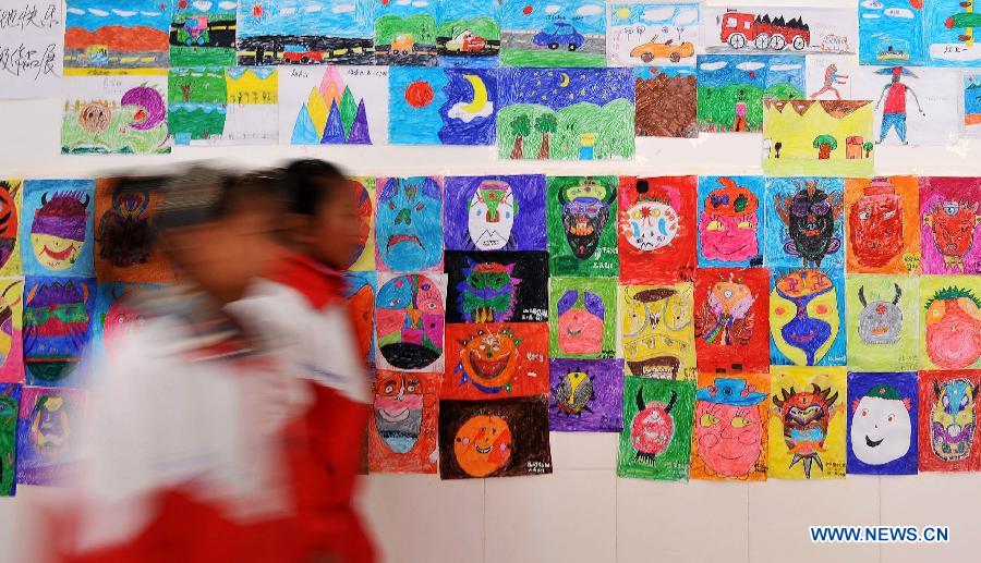 Pupils of the Tibetan ethnic group walk past the painting works of their schoolmates at No. 1 Primary School of Deqin County in Diqing Tibetan Autonomous Prefecture, southwest China's Yunnan Province, March 12, 2013. 