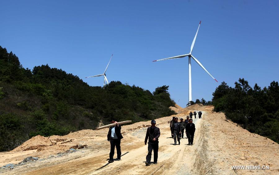 People walk on a road near the Bijiashan Wind Power Plant beside the Poyang Lake in Jiujiang City, east China's Jiangxi Province, April 7, 2013.