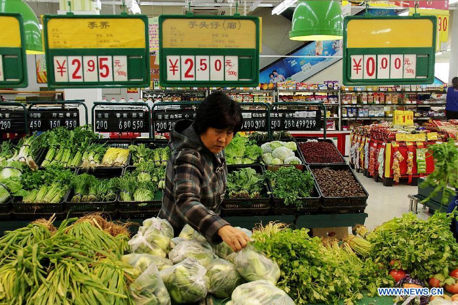 A woman chooses vegetables at a supermarket in Bazhou City, north China's Hebei Province, April 8, 2013. 