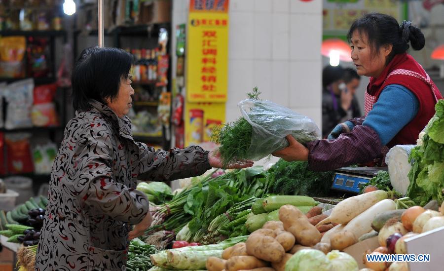 A citizen buys vegetables at a market in Shijiazhuang City, north China's Hebei Province, April 9, 2013. 