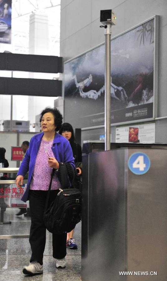 A passenger walks past the infrared temperature measuring instrument at the Baiyun International Airport in Guangzhou, capital of south China's Guangdong Province, April 17, 2013. 