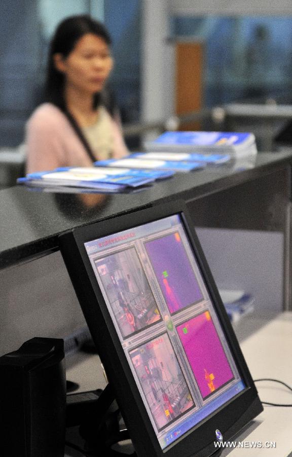 A passenger walks past the infrared temperature measuring instrument at the Baiyun International Airport in Guangzhou, capital of south China's Guangdong Province, April 17, 2013.