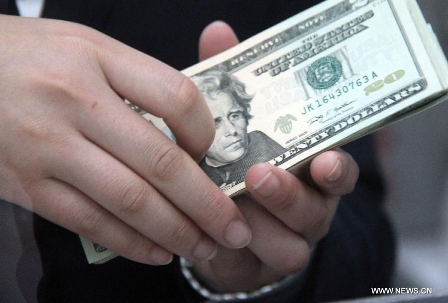 A worker counts U.S. dollar banknotes at a bank in Tancheng County of Linyi City, east China&apos;s Shandong Province, May 8, 2013. 