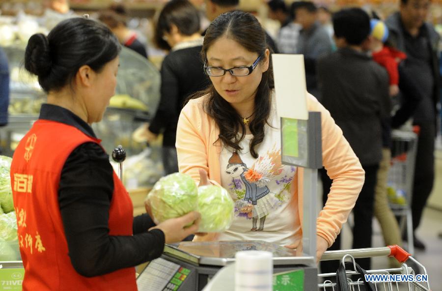 A consumer weighs vegetable at a supermarket in Yinchuan, capital of northwest China's Ningxia Hui Autonomous Region, May 8, 2013. 