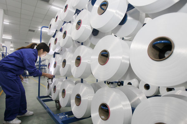 A technician inspects textile materials in Nantong, Jiangsu Province. China is competitive in some industries such as textiles, but it needs to take steps to sharpen its competitive edge.