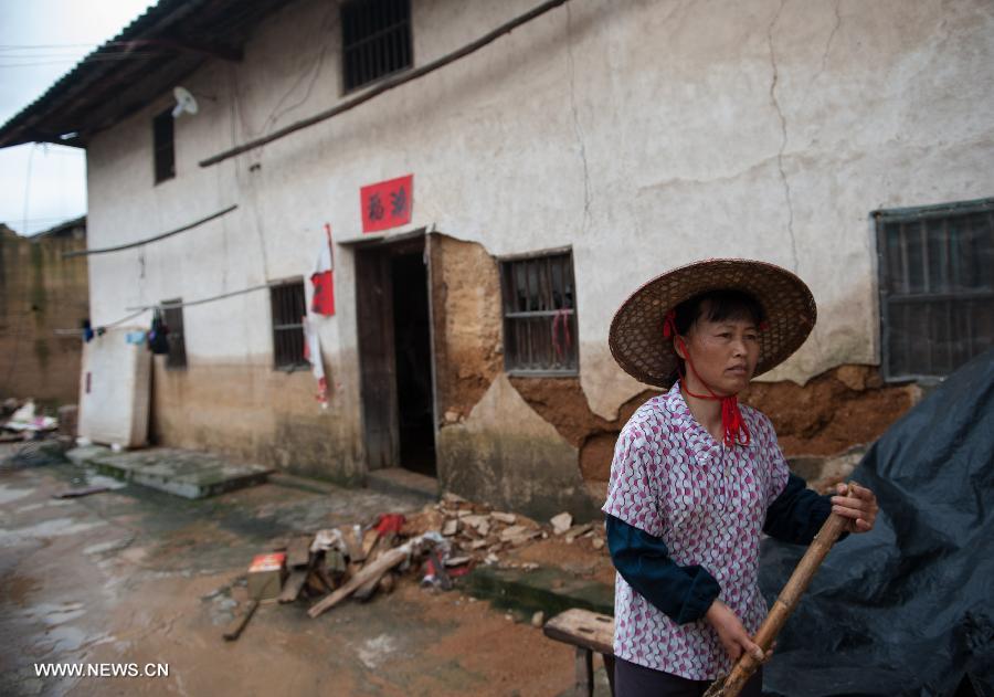 Zhong Weimei, 50, cleans in front of her house in Haoling Village of Jiaoling County, Meizhou City, South China's Guangdong Province, May 22, 2013. 