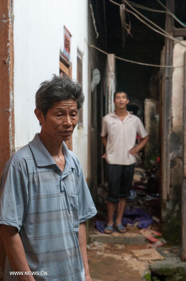 Zhong Yongxiang (front), 59, and his 27-year-old son Zhong Yun stand in their flooded house in Legan Village of Jiaoling County, Meizhou City, South China's Guangdong Province, May 23, 2013.