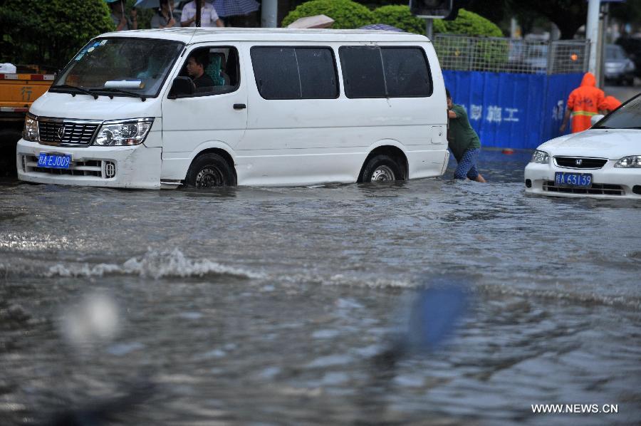 A man tries to push a vehicle trapped in floods in Nanning City, south China's Guangxi Zhuang Autonomous Region, June 4, 2013.