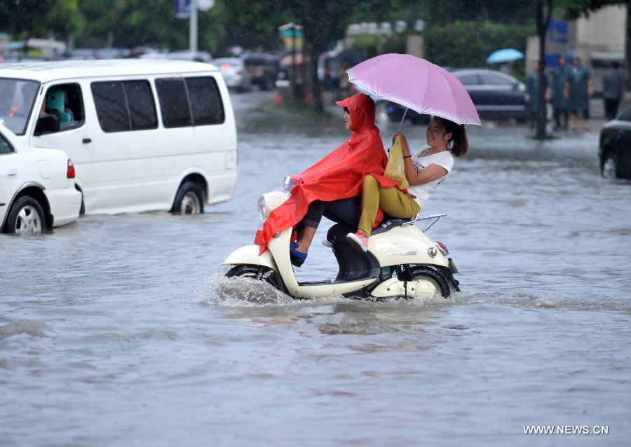 People ride an electric bike in floods in Nanning City, south China's Guangxi Zhuang Autonomous Region, June 4, 2013.