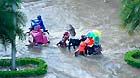 People ride in floods in Nanning City, south China's Guangxi Zhuang Autonomous Region, June 4, 2013.
