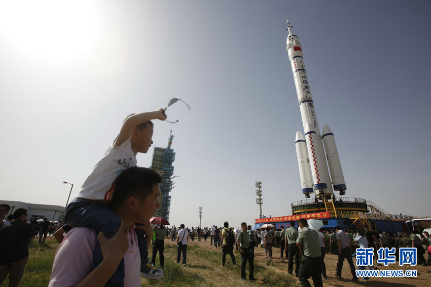 The Shenzhou 10 spacecraft, atop its Long March-2F carrier rocket booster, has been vertically transferred from a preparation area to the launch pad at the Jiuquan Satellite Launch Center in the Gobi desert. 