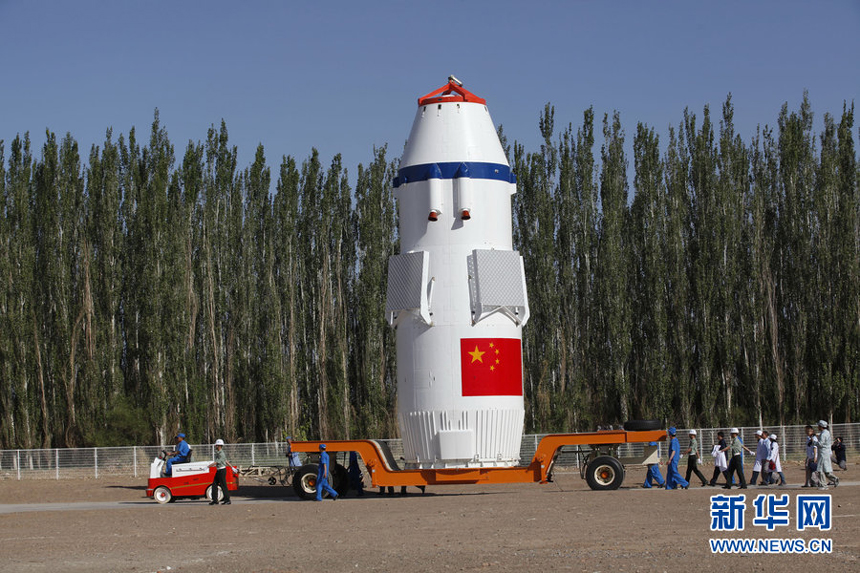 The Shenzhou 10 spacecraft, atop its Long March-2F carrier rocket booster, has been vertically transferred from a preparation area to the launch pad at the Jiuquan Satellite Launch Center in the Gobi desert. 