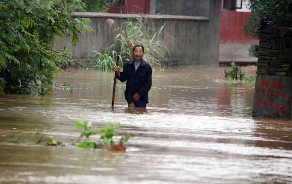 A villager walks on a flooded road in Gangdong Village, Duchang County, Jiangxi Province on June 7, 2013.