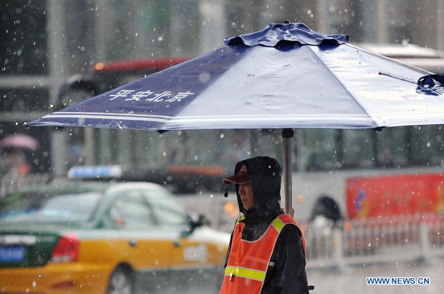 A traffic coordinator is on duty in rain and hail in Beijing, capital of Beijing, June 11, 2013. (Xinhua/Chen Yehua) 
