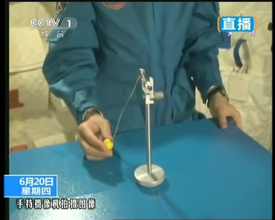 This TV grab taken on June 20, 2013 shows female astronaut Wang Yaping, one of the three crew members of Shenzhou-10 spacecraft, demonstrating pendulum movement in space during a lecture to students on Earth aboard China's space module Tiangong-1. 