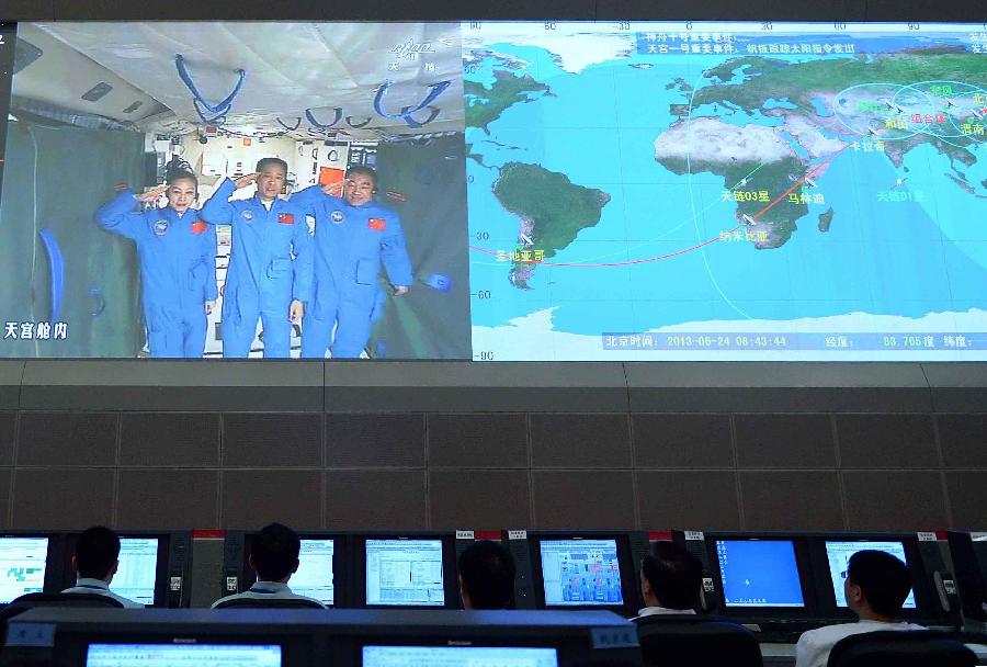 Photo taken on June 24, 2013 shows the screen at the Beijing Aerospace Control Center showing astronauts Nie Haisheng (C), Zhang Xiaoguang (R) and Wang Yaping saluting in Tiangong-1 space lab module. Chinese President Xi Jinping came to the Beijing Aerospace Control Center Monday morning to talk with the astronauts aboard Tiangong-1. 