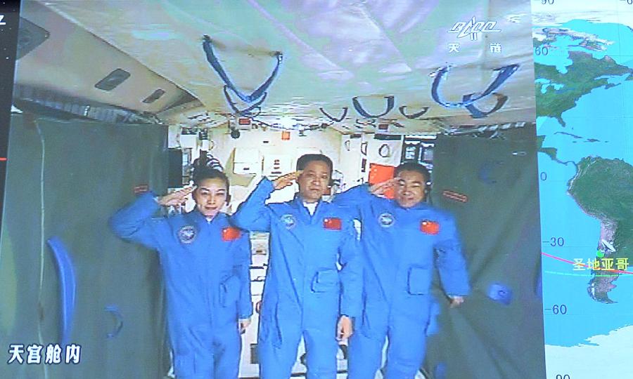Photo taken on June 24, 2013 shows the screen at the Beijing Aerospace Control Center showing astronauts Nie Haisheng (C), Zhang Xiaoguang (R) and Wang Yaping saluting in Tiangong-1 space lab module. Chinese President Xi Jinping came to the Beijing Aerospace Control Center Monday morning to talk with the astronauts aboard Tiangong-1.