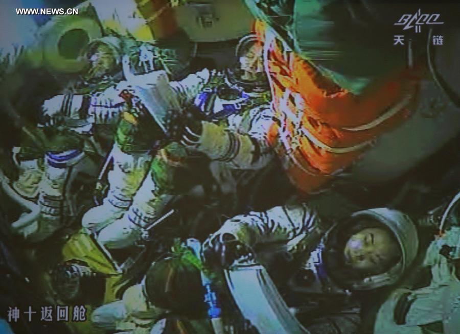 The screen at the Beijing Aerospace Control Center shows the three astronauts having prepared for the return of the Shenzhou-10 spacecraft to earth on June 26, 2013. 