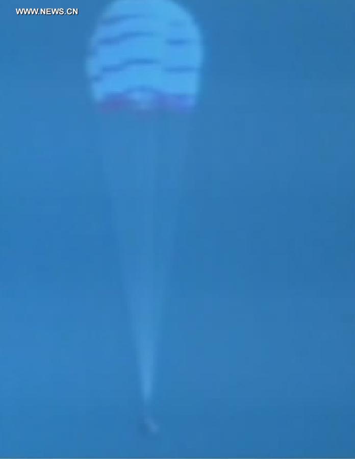 The screenshot shows the opening of the main parachute of the re-entry capsule of China's Shenzhou-10 spacecraft during its return to earth on June 26, 2013. 