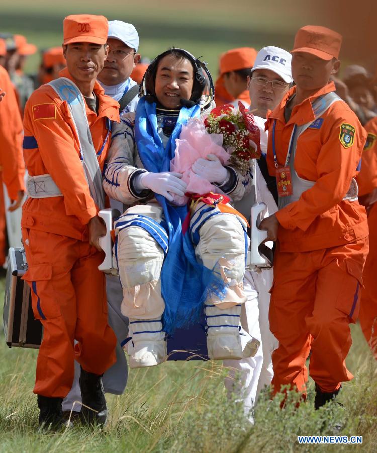 Astronaut Zhang Xiaoguang is escorted to board a helicopter for medical care after getting out of the re-entry capsule of China's Shenzhou-10 spacecraft following its successful landing at the main landing site in north China's Inner Mongolia Autonomous Region on June 26, 2013.