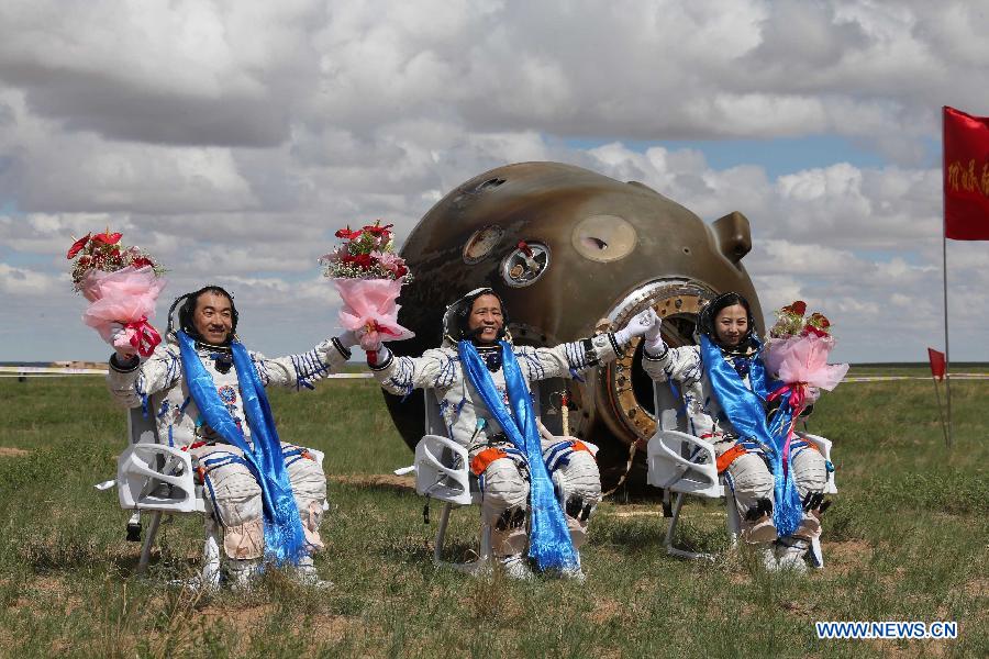 Astronauts Zhang Xiaoguang, Nie Haisheng and Wang Yaping (from left to right) greet the people after getting out of the re-entry capsule of China's Shenzhou-10 spacecraft following its successful landing at the main landing site in north China's Inner Mongolia Autonomous Region on June 26, 2013. (Xinhua/Wang Jianmin) 