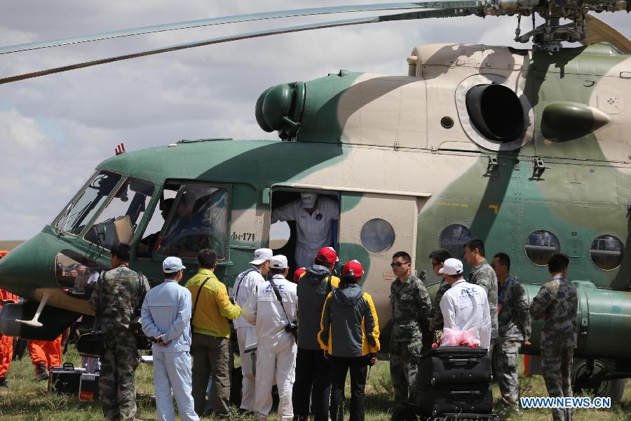 Astronauts are escorted to board a helicopter for medical care after getting out of the re-entry capsule of China's Shenzhou-10 spacecraft following its successful landing at the main landing site in north China's Inner Mongolia Autonomous Region on June 26, 2013.