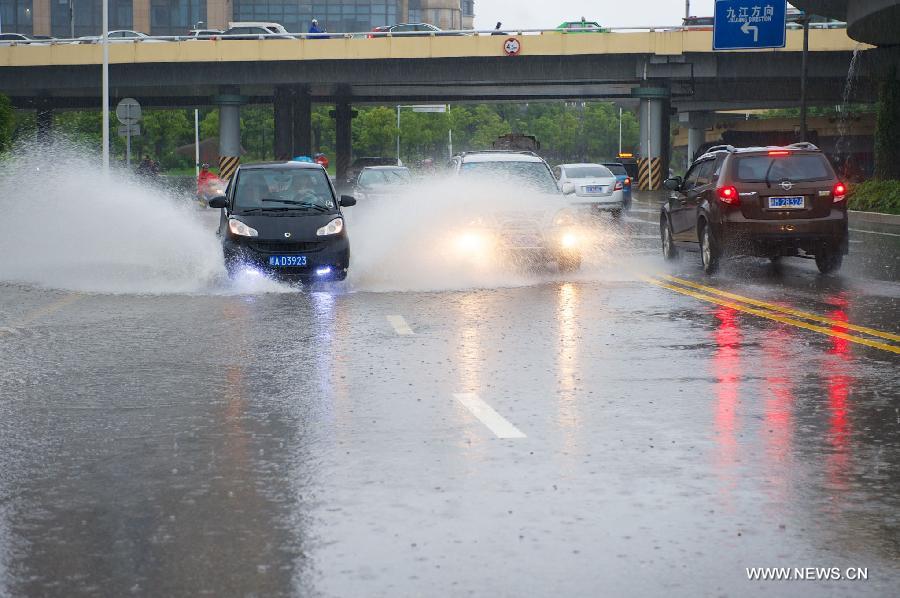 Vehicles run on a waterlogged road in rain in Nanchang, capital of east China's Jiangxi Province, June 28, 2013. Heavy rainfall hit parts of the province on Friday. 