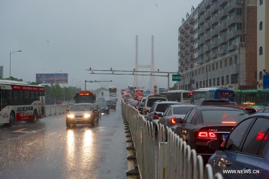 Vehicles run on a waterlogged road in rain in Nanchang, capital of east China's Jiangxi Province, June 28, 2013. 