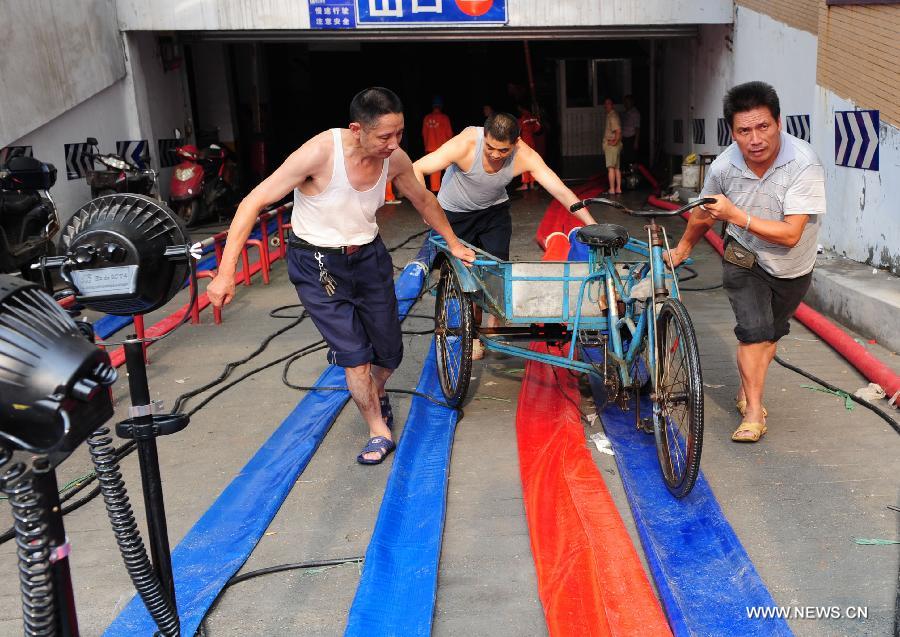 Residents push a tricycle out of a flooded underground parking lot in Suining, southwest China's Sichuan Province, July 2, 2013. 