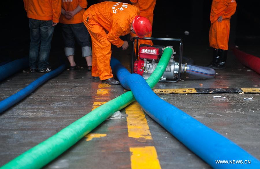 People pump water from a flooded underground parking lot in Suining, southwest China&apos;s Sichuan Province, July 2, 2013. 