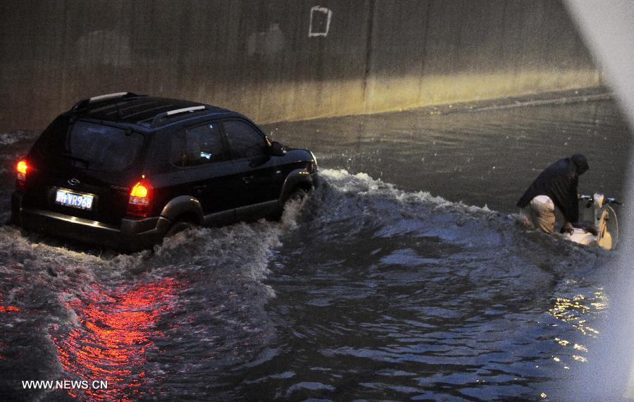 A vehicle moves on a waterlogged road in Tianjin, north China, July 4, 2013. 
