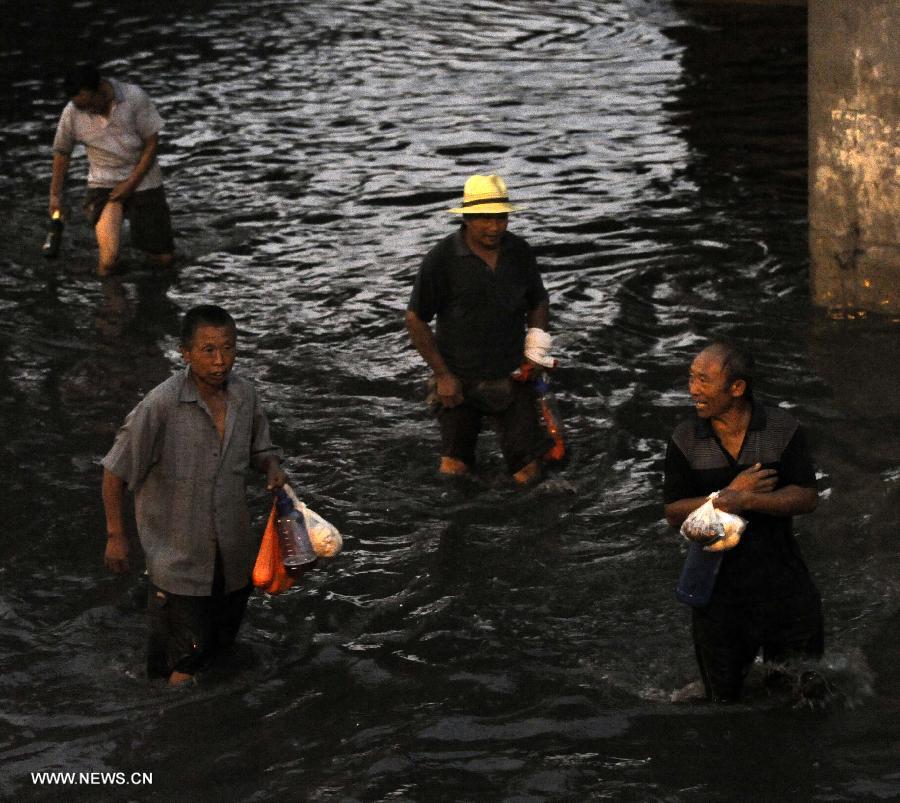 Pedestrains walk on a waterlogged road in Tianjin, north China, July 4, 2013. 