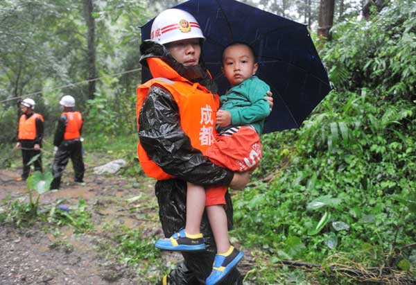 A child is evacuated from the landslide site in Zhongxing, a town in Dujiangyan, Sichuan Province, on Wednesday. At least two people were killed.