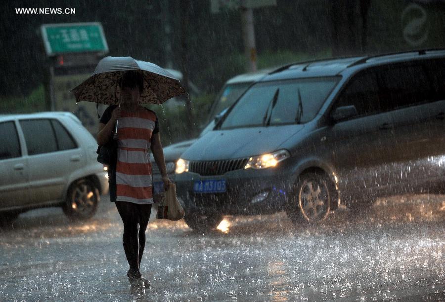 A passenger walks in torrential rain on the Yuhan Road in Jinan, capital of east China&apos;s Shandong Province, July 29, 2013. 