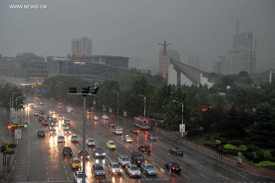 Vehicles travel in torrential rain in a street in Jinan, capital of east China&apos;s Shandong Province, July 29, 2013. 