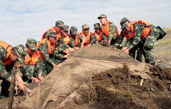 Government rescue workers help clean the debris left by a flood in Qinghai Province on Wednesday. Rain and hail battered Wulan County in the Mongolian-Tibetan Autonomous Prefecture of Haixi on Tuesday, and authorities said on Wednesday that the death toll had reached 24.