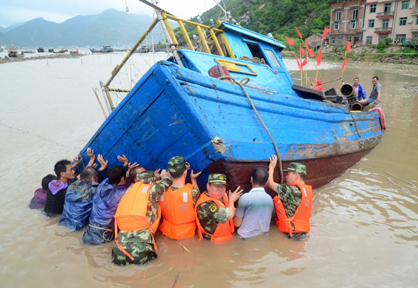 Troops and fishermen try to move a boat to a safer spot in Xiapu, Fujian Province, on Thursday, after it was overturned by the powerful winds of Typhoon Trami.