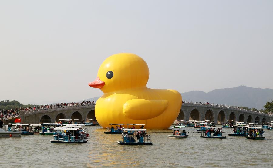 Tourists watch the giant rubber duck, the brainchild of Dutch artist Florentijn Hofman, at the Summer Palace in Beijing, capital of China, Oct. 7, 2013, the last day of the seven-day National Day holiday. 