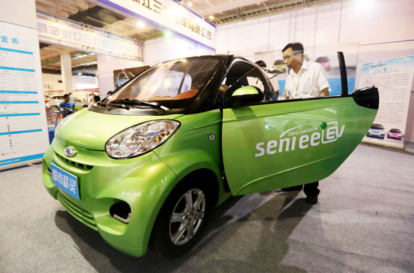 A man checks out an electric mobile at a new energy auto show in Beijing in July. The capital plans to tackle air pollution by promoting the use of green vehicles and cutting annual gasoline and diesel fuel consumption.