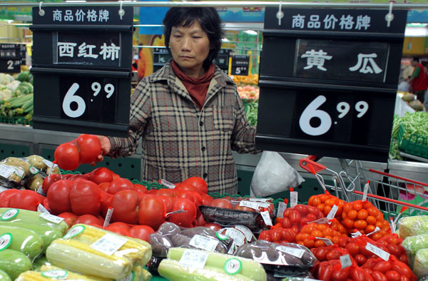 A woman pickes tomatoes in a market.