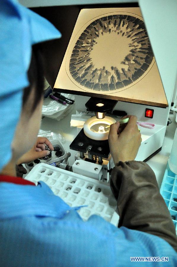 A worker checks the newly produced contact lenses in a factory of the CST Automation Technology CO., LTD, a non-public enterprise, in Baiyin City, northwest China&apos;s Gansu Province, Oct. 31, 2013. 