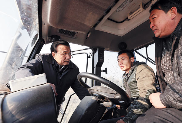 Premier Li Keqiang talks to farmers in the cab of an agricultural vehicle in Fuyuan, Heilongjiang Province, on Tuesday. A rare flood hit the county in August, threatening the harvest.