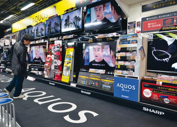 A customer looks at LCD television sets made by Japanese multinational Sharp Corp at a store in Tokyo. Asian corporations need to make branding an integrated part of all strategy decisions for their products to compete in the global league.