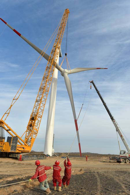 Turbine blades are hoisted onto a windmill at a wind farm in Hami, in the Xinjiang Uygur Autonomous Region. Xinjiang is one of the biggest wind-power generating regions in China. The country is trying to increase the proportion of renewable energy in its total energy consumption mixture.