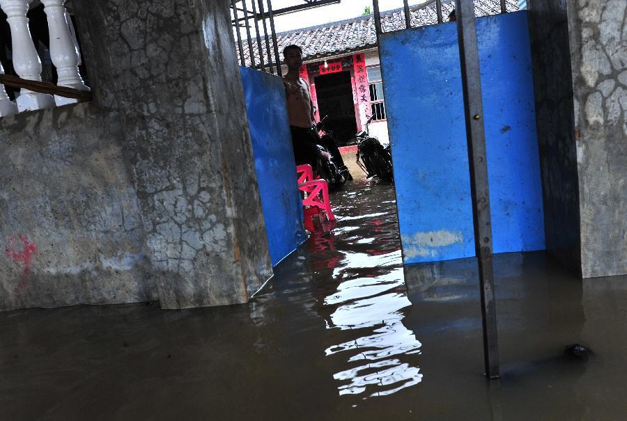 Local resident Wang Jinmin stands in his flooded home in Wanning City, south China's Hainan Province, Dec. 15, 2013. Heavy rain continued to hit Wanning City from Friday night to Sunday. A total of 80,000 residents have been transferred to safe regions. (Xinhua/Zhang Yongfeng)