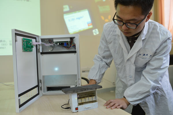 A member of the Shanghai Jiao Tong University research team that invented a new air-purifying device demonstrates the machine. The device’s technology can prevent secondary pollution that existing air purifiers can create if not used properly. Du Xin / for China Daily