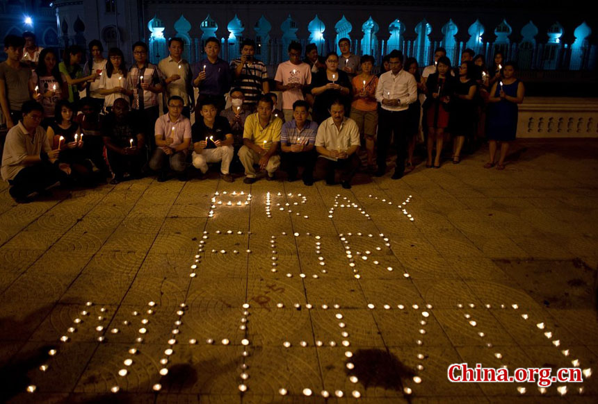 A group of Malaysian residents pose after lighting candles during a vigil for missing Malaysia Airlines passengers at the Independence Square in Kuala Lumpur on March 10, 2014.