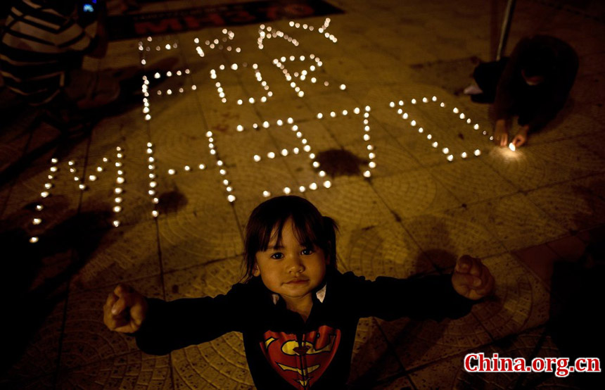 A group of Malaysian residents pose after lighting candles during a vigil for missing Malaysia Airlines passengers at the Independence Square in Kuala Lumpur on March 10, 2014.