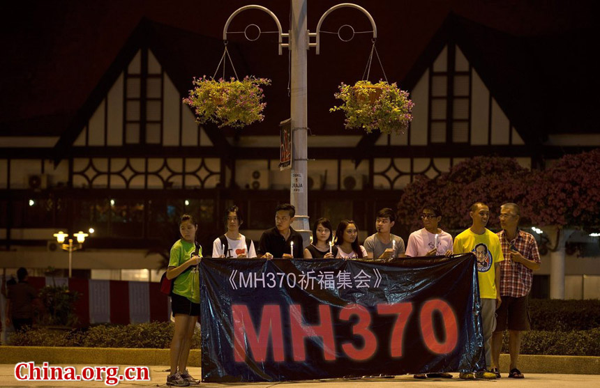 A group of Malaysian residents hold a banner and candles during a vigil for missing Malaysia Airlines passengers at the Independence Square in Kuala Lumpur on March 10, 2014.