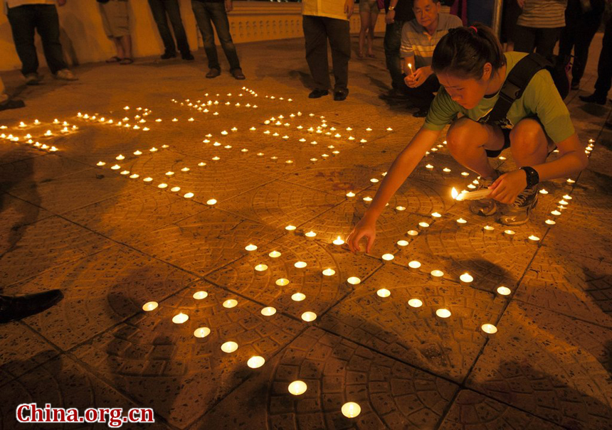 A Malaysian lights a candle to form a slogan during a vigil for the missing Malaysia Airlines passengers, in Kuala Lumpur, Malaysia, 10 May 2014. 